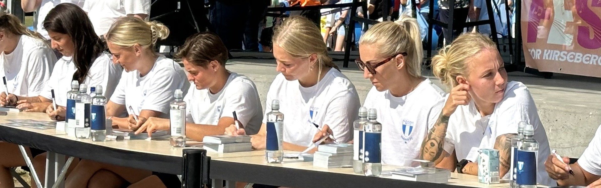 Malmö FFs damlag sitter och skriver autografer