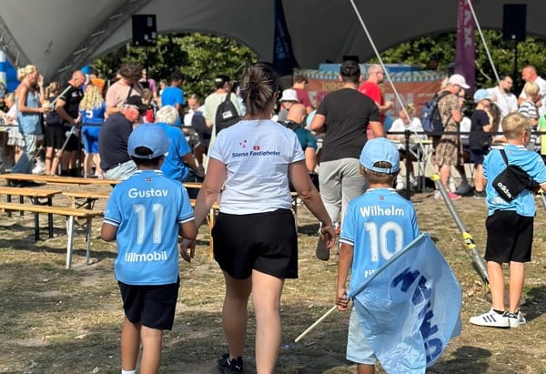 Två barn med Malmö FF kläder som håller i sin mammas hand med Stena Fastigheter tröja